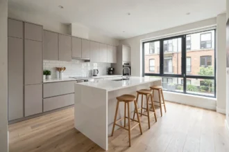 Cuisine moderne ouverte avec îlot central en quartz blanc et parquet chêne dans un appartement spacieux